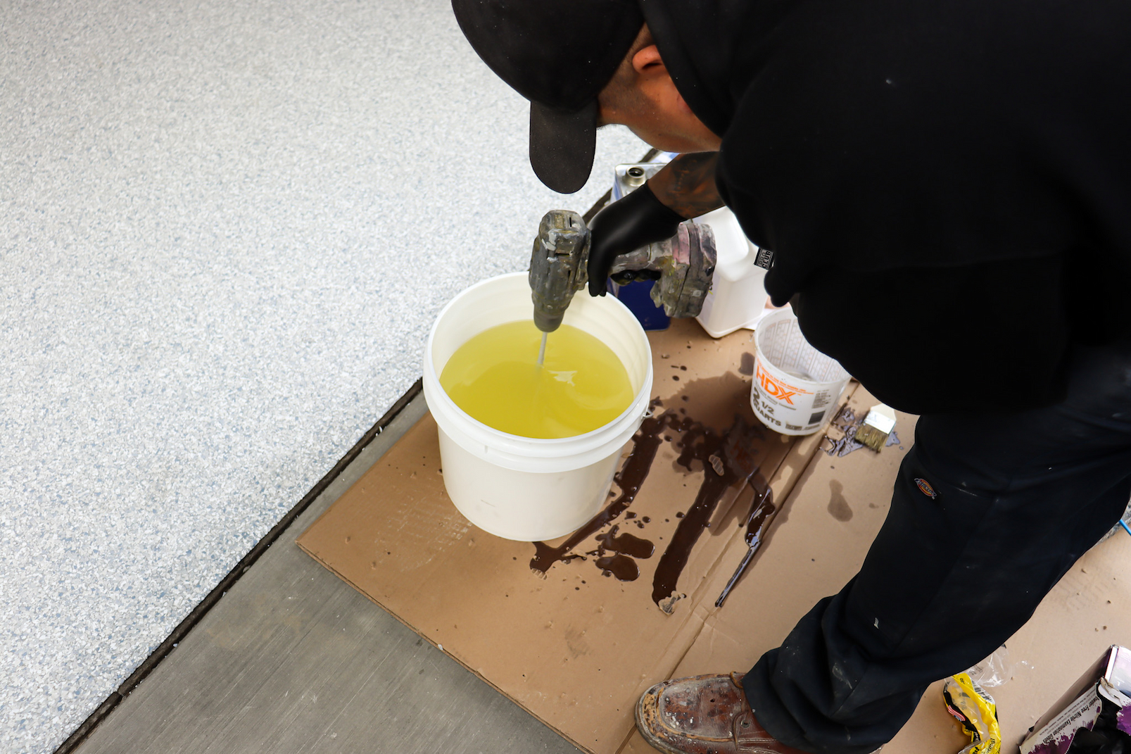 installer mixing garage floor coating product before application in residential garage