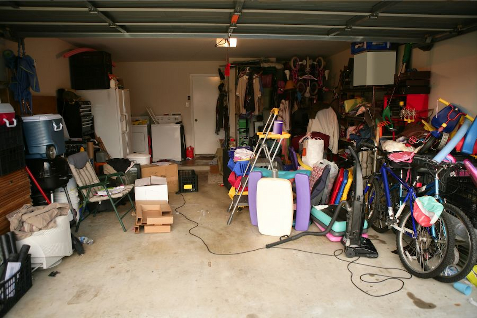 disorganized garage with cluttered storage bins tools and gear